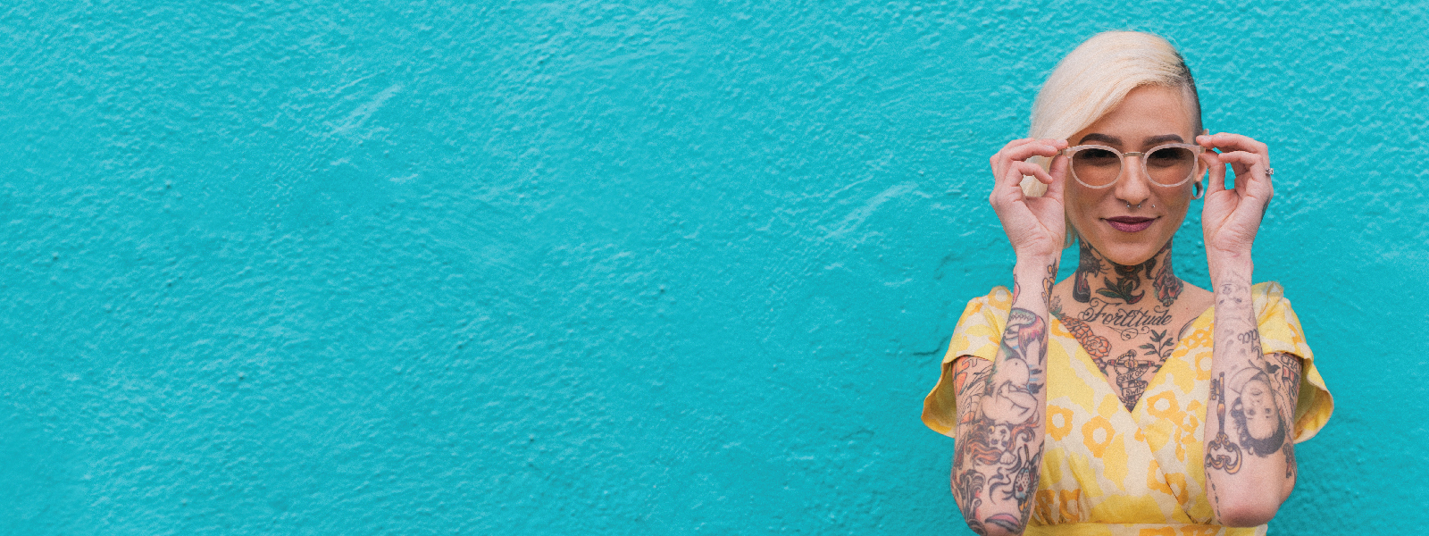 LDC_46541_WEB_1600x600px-141 girl with tattoos and glasses against a blue wall